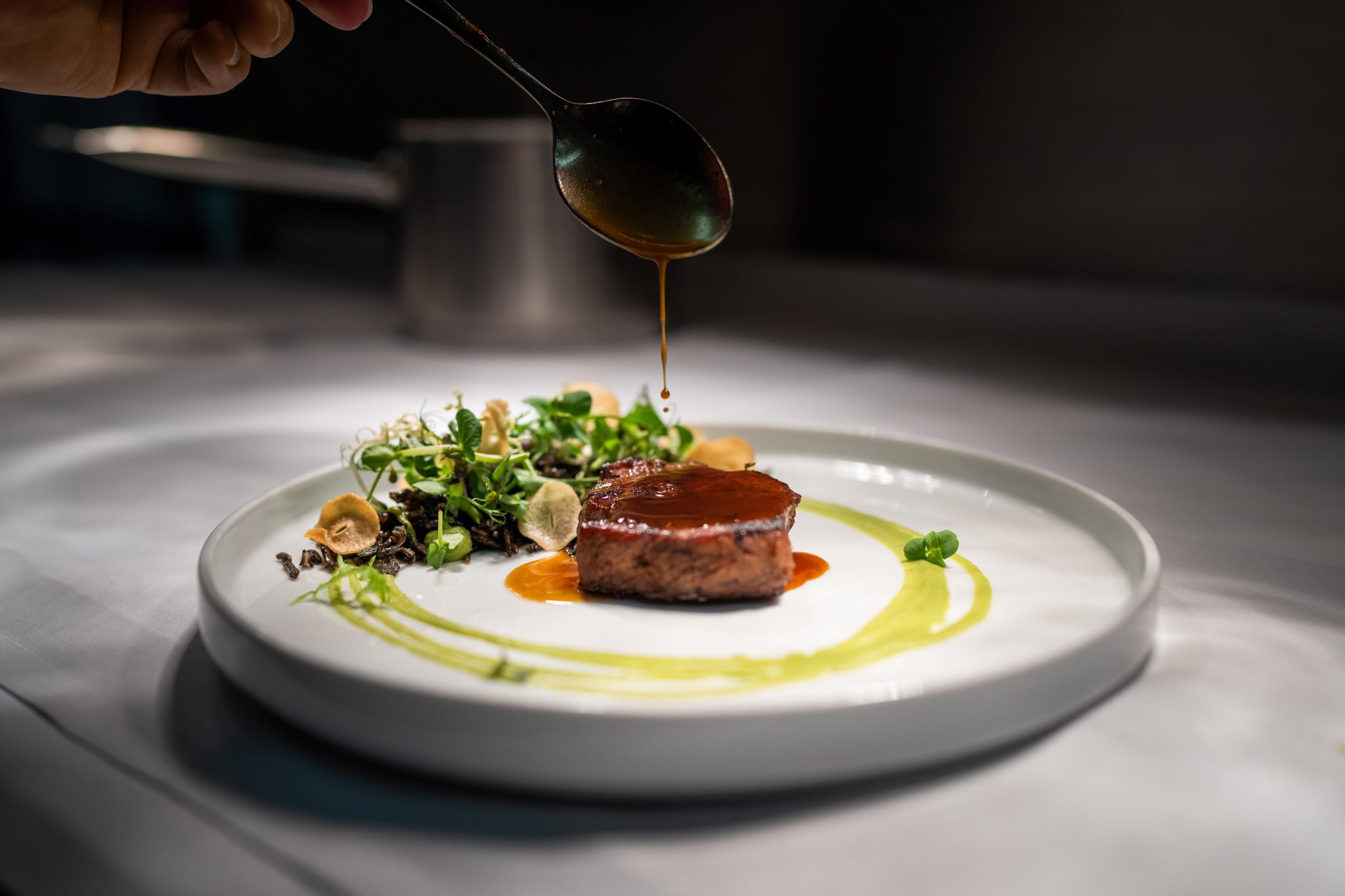 Anrichten einer Hauptspeise, Steak mit Sauce und frischen Kräutern